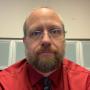 picture of Samuel Bachert, beard, glasses, red shirt and tie