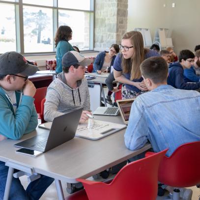 Teaching assistant working with three student at work table